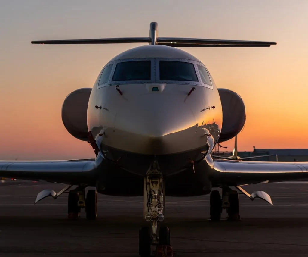 Private jet parked on the apron at sunset, seen nose-on