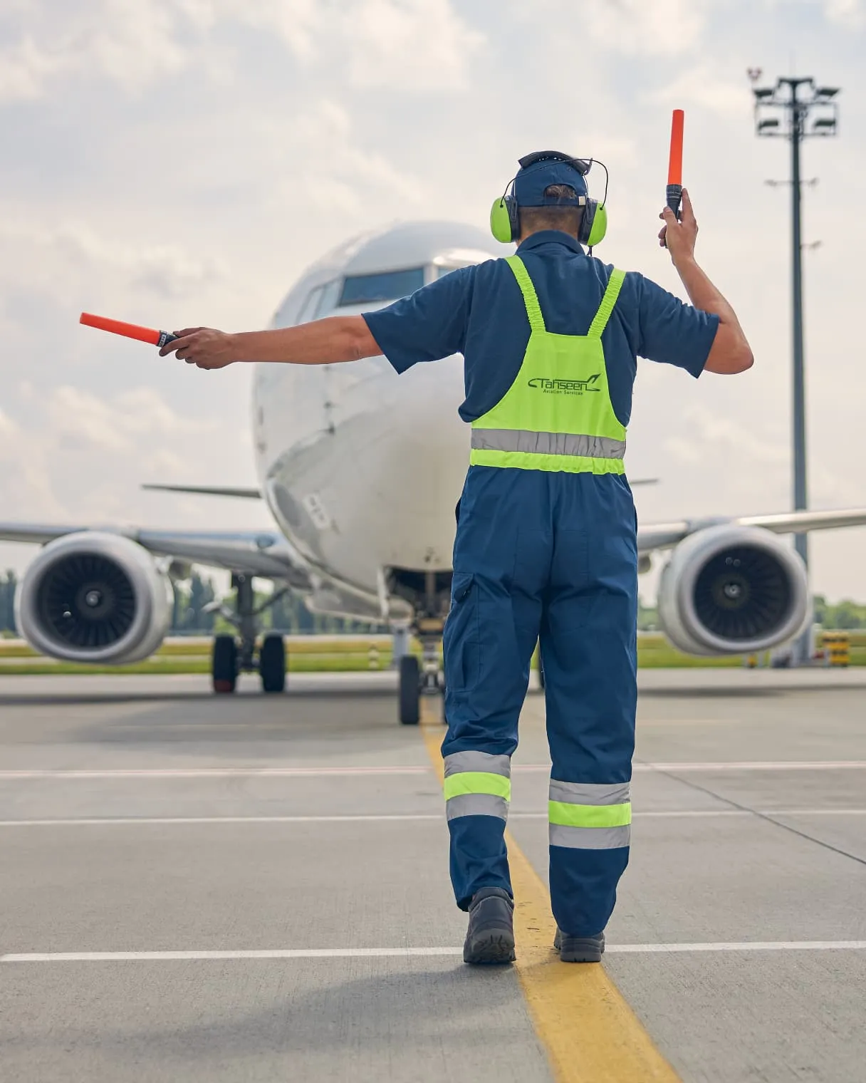 Tahseen Aviation ground handler marshalling an airliner on the apron