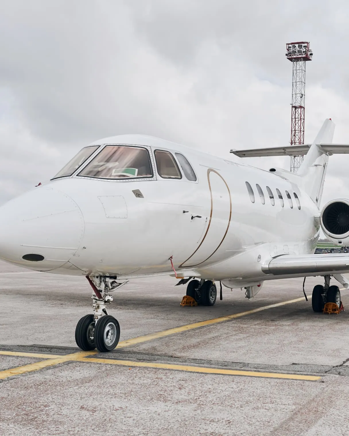 White private jet parked on the apron with wheel chocks in place