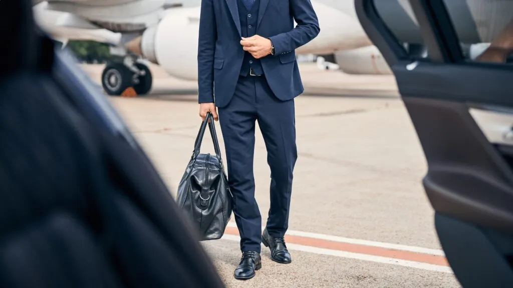 Official in a suit walking from an aircraft to a waiting car