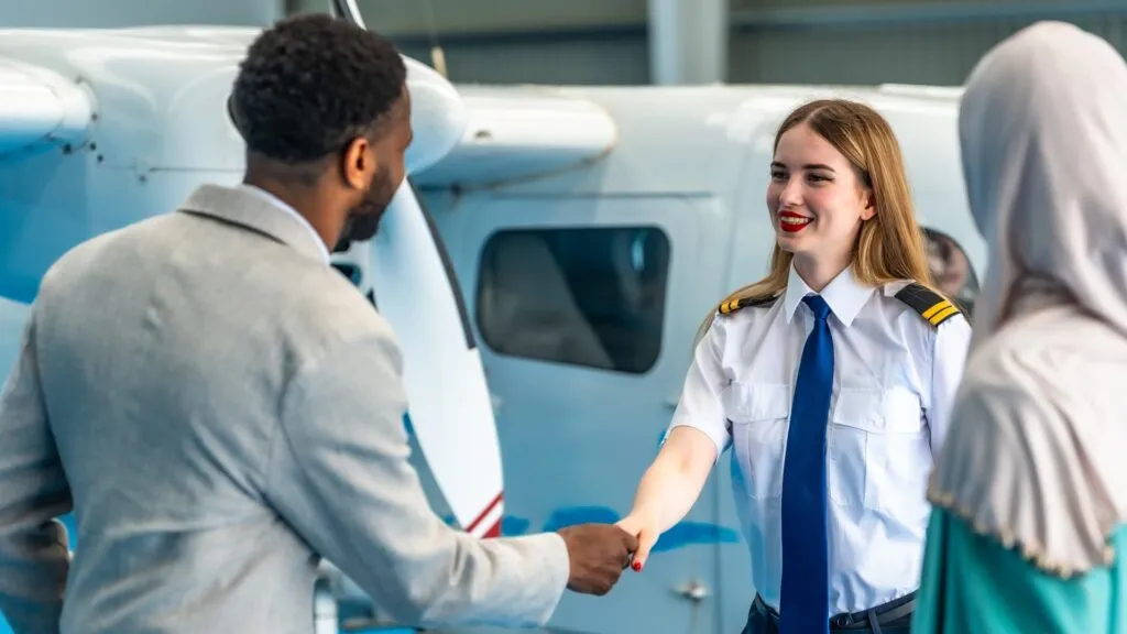 Pilot shaking hands with a client in front of an aircraft in a hangar